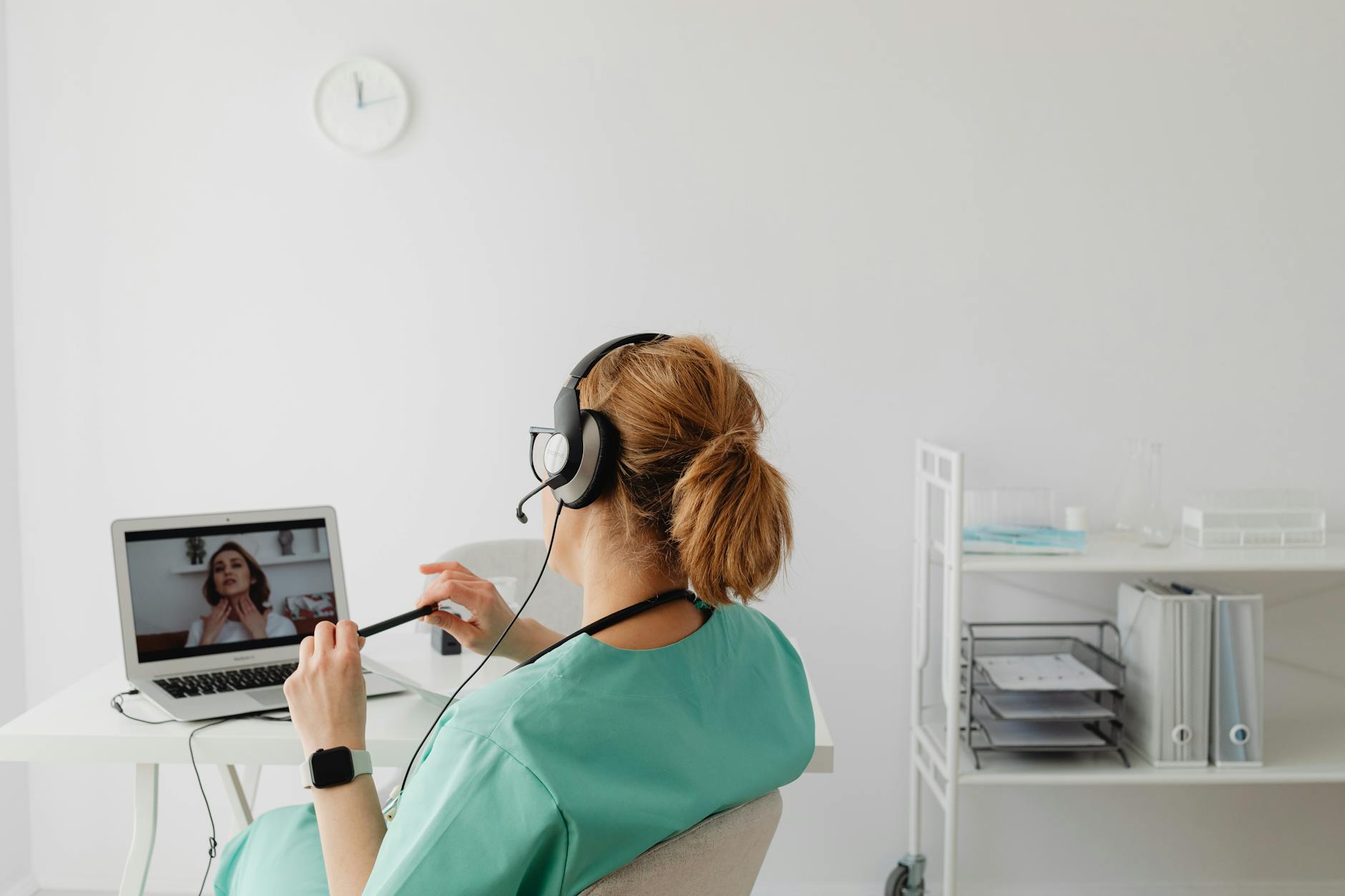 woman in teal scrub suit on a video call